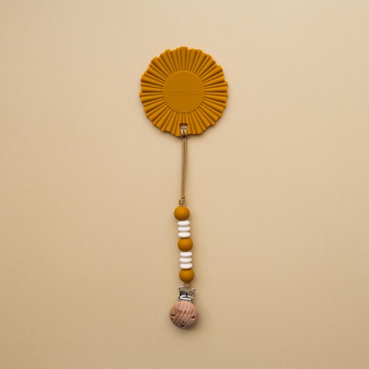 Beige background with Ochre Clip and Boho Sun Teether by Minika. Teether is an ochre sun, with silicone beads in ochre and white and a wood clip.