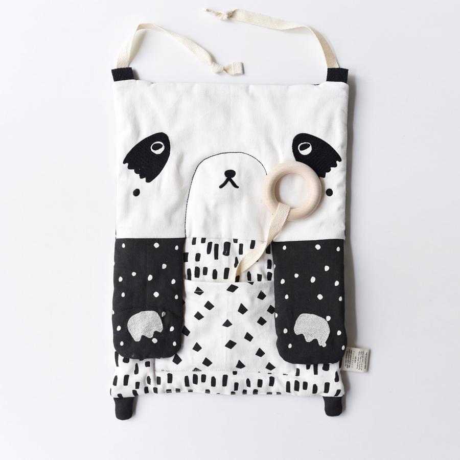 White background with the Peekaboo Panda Organic Activity Pad by Wee Gallery. Activity pad looks like a pandas face, all done in black and white, with a teething ring attached with canvas.