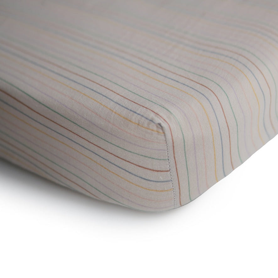 Extra Soft Muslin Crib Sheet in Retro Stripe by Mushie on a mattress with a white background. 