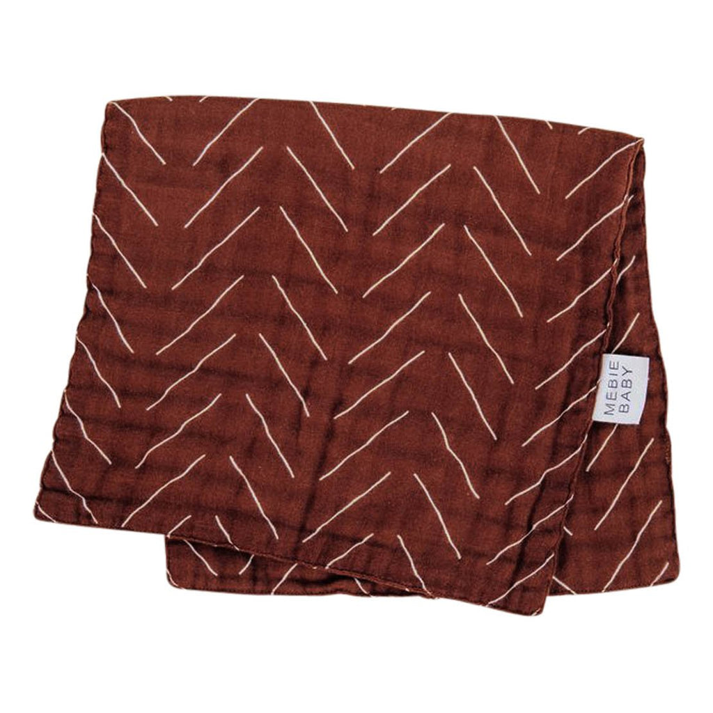 White background with folded Rust Mudcloth Burp Cloth by Mebie Baby. Burp cloth is rust with white lines.