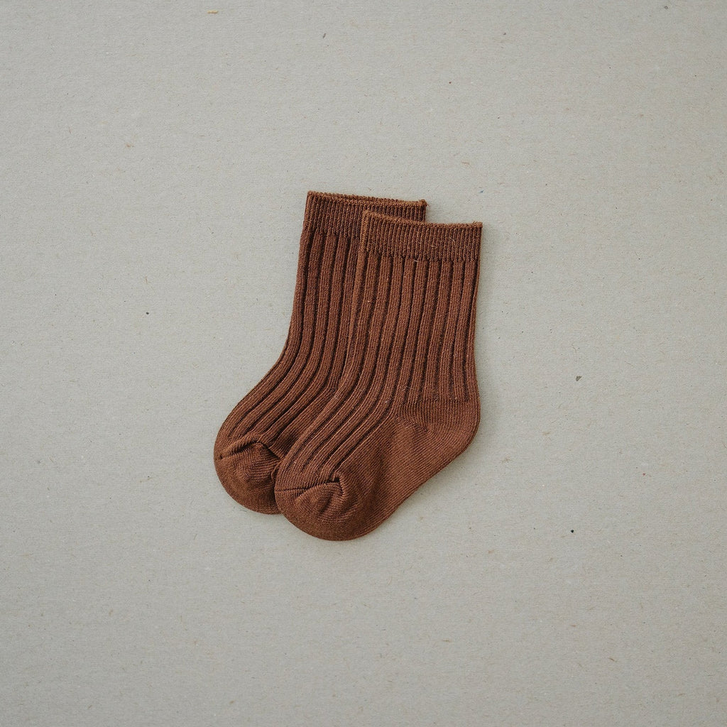 Rust Socks by Mebie Baby with a greige background. 