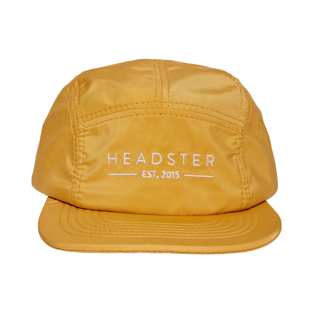 Clear background with Salty 5 Panel Hat in Sunny Day by Headster. 5 Panel Hat is a yellow colour with white stitched writing that says "Headster" across the front.