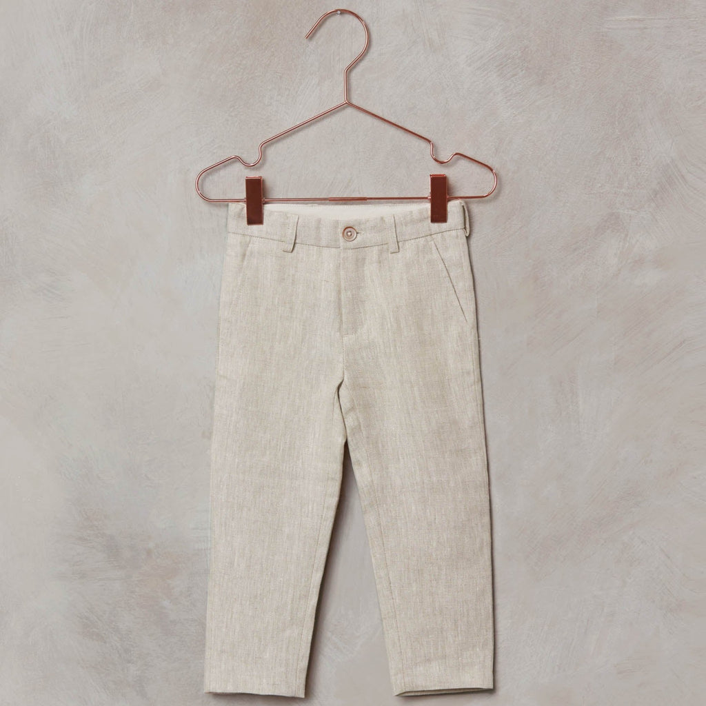 Grey background with a rose gold hanger, and the Sebastian Pant by Noralee in Linen. Pants are a straight leg, with a wood button, in a linen colour.