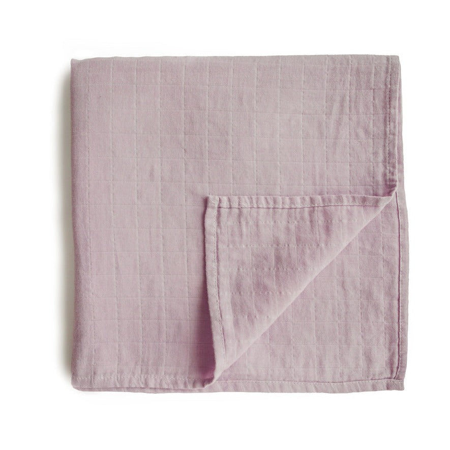 Muslin Swaddle Blanket Organic Cotton in Soft Mauve by Mushie, folded on a flat white surface. 