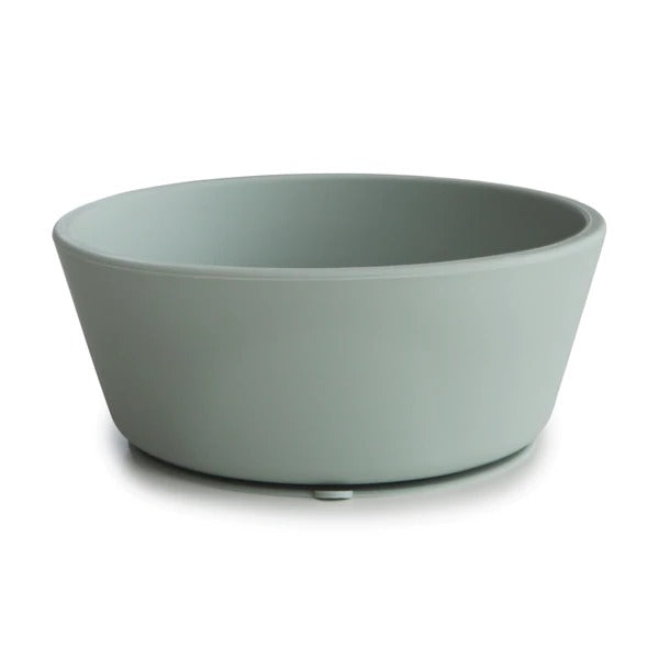 White background with Silicone Suction Bowl in Cambridge Blue by Mushie. Bowl has a suction base, and is blue.