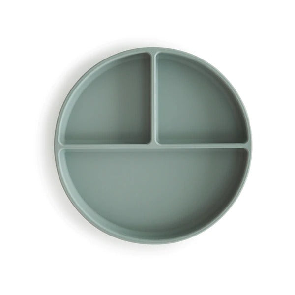 White background with a Silicone Suction Plate in Cambridge Blue by Mushie. Plate is rounded with 3 compartments, 2 smaller, and 1 larger, in a green/blue colour.