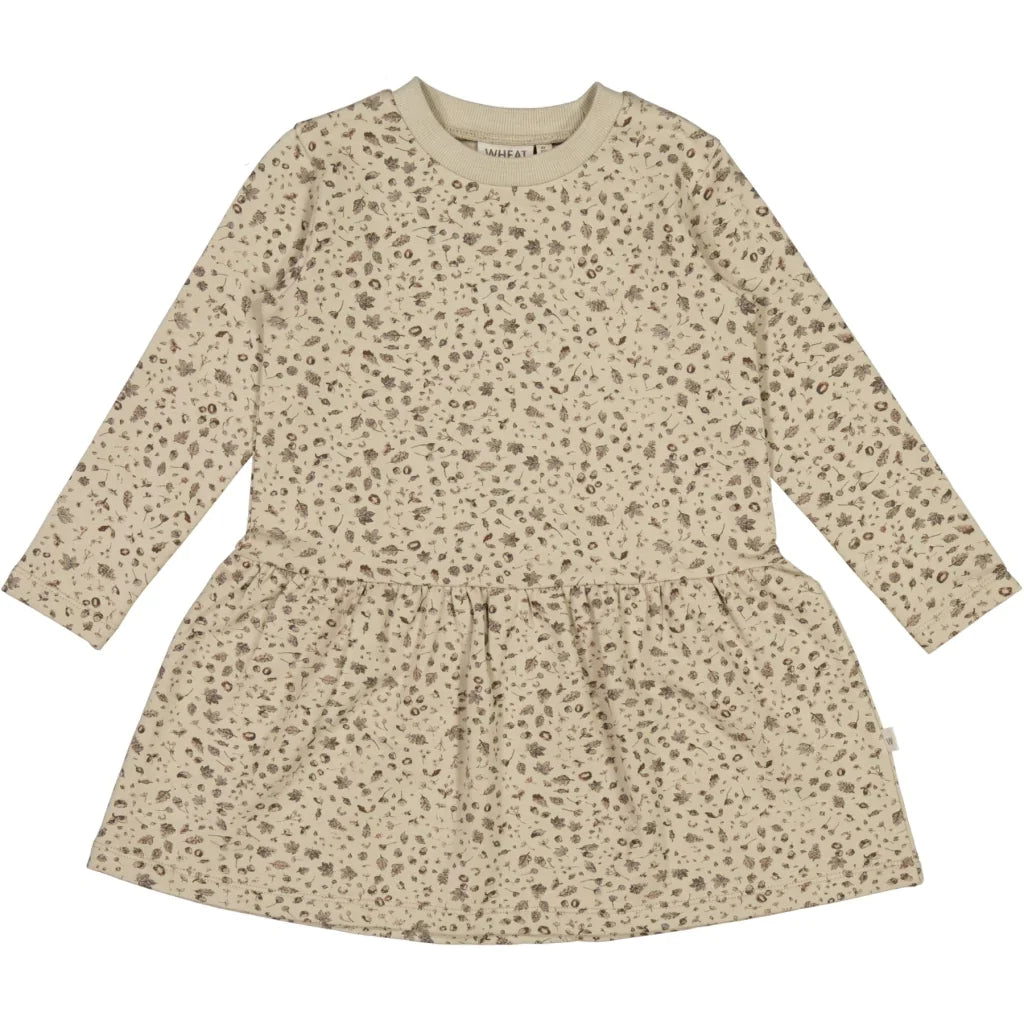 White background with Sweat Dress Tascha in Gravel & Spruce by Wheat Kids Clothing. This shows the kids dress, which has a smaller print. Dress is a grey/cream colour with a drop waist, and a gravel and spruce pattern all over.