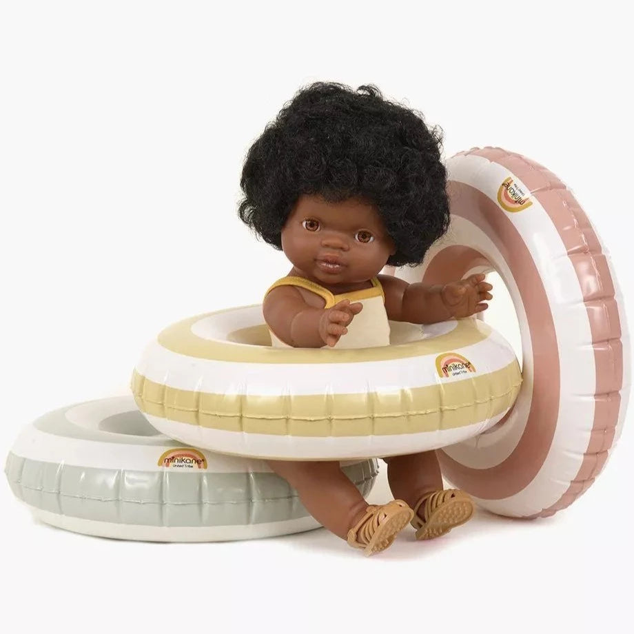 White background with a stack of Swim Ring for Dolls by Minikane, with a doll inside one of them.