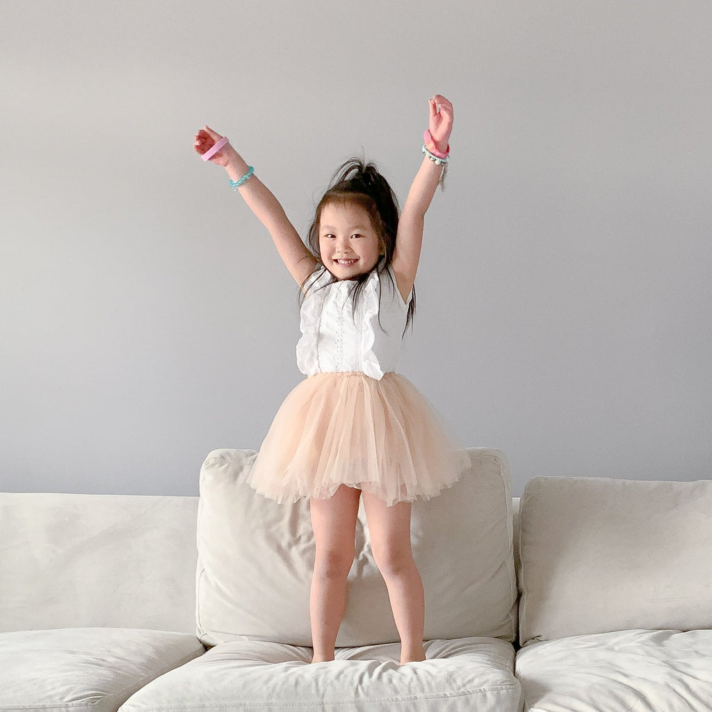 Little girl standing with arms in the air wearing a taupe celine tutu by Bluish