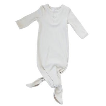 White background with Vanilla Organic Cotton Ribbed Knot Gown by Mebie Baby. Knot gown is white ribbed with 2 buttons down the front, and a knot tie closure at the bottom.