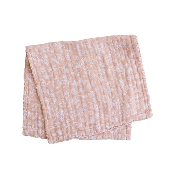 White background with a folded Wildflower Burp Cloth by Mebie Baby. Burp cloth is a soft pink  with white wildflowers all over.