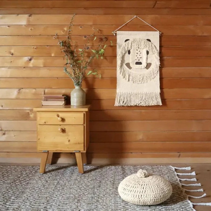 Wood panel wall with a small table, with greenery in a vase, and a Leopold Wall Decor by Nattiot. Wall decor looks like a lion with a shaggy mane.