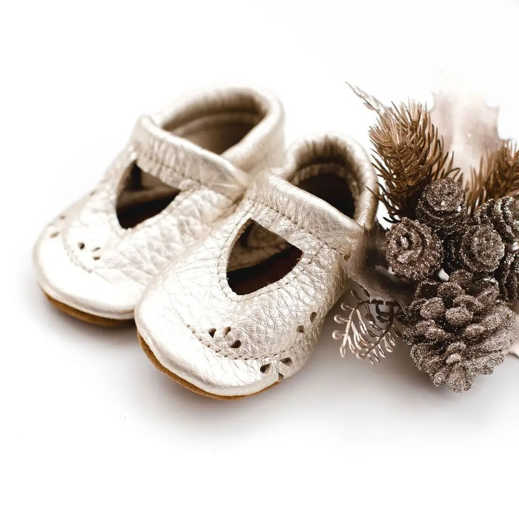 White background with glittery pinecones, and the Platinum Ivy Janes by Starry Knight Design. Shoes are a silver colour. 